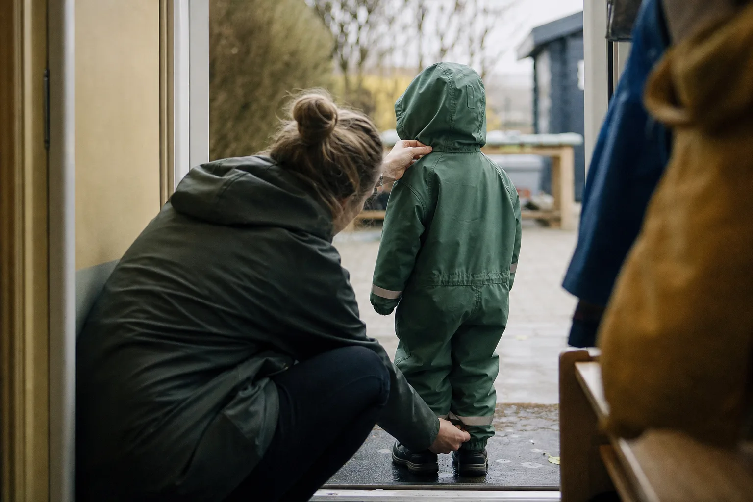 Un adulto comprueba la capucha y el bajo del tobillo del mono de lluvia de un niño