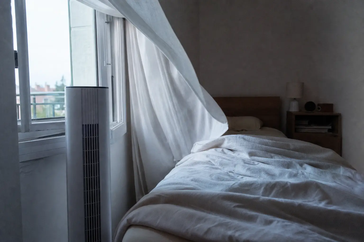 Turmventilator neben einem schmalen Bett und offenem Fenster