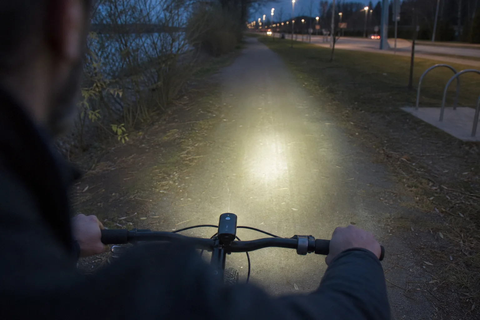 Ciclista entrando en un camino sin iluminación con la luz delantera encendida