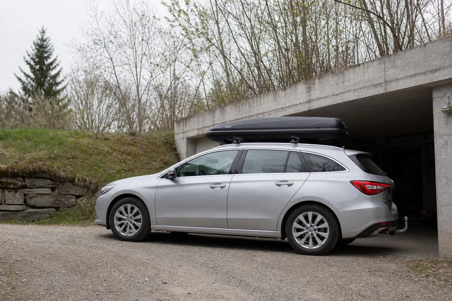 Auto mit Dachbox unter einer niedrigen Garagenkante